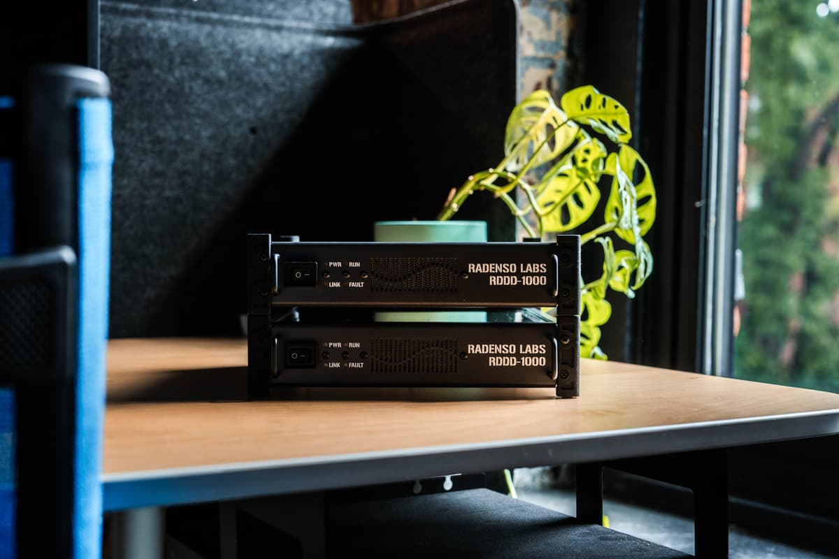 Two stacked Radenso Labs RDDD-1000 units on a table beside a window